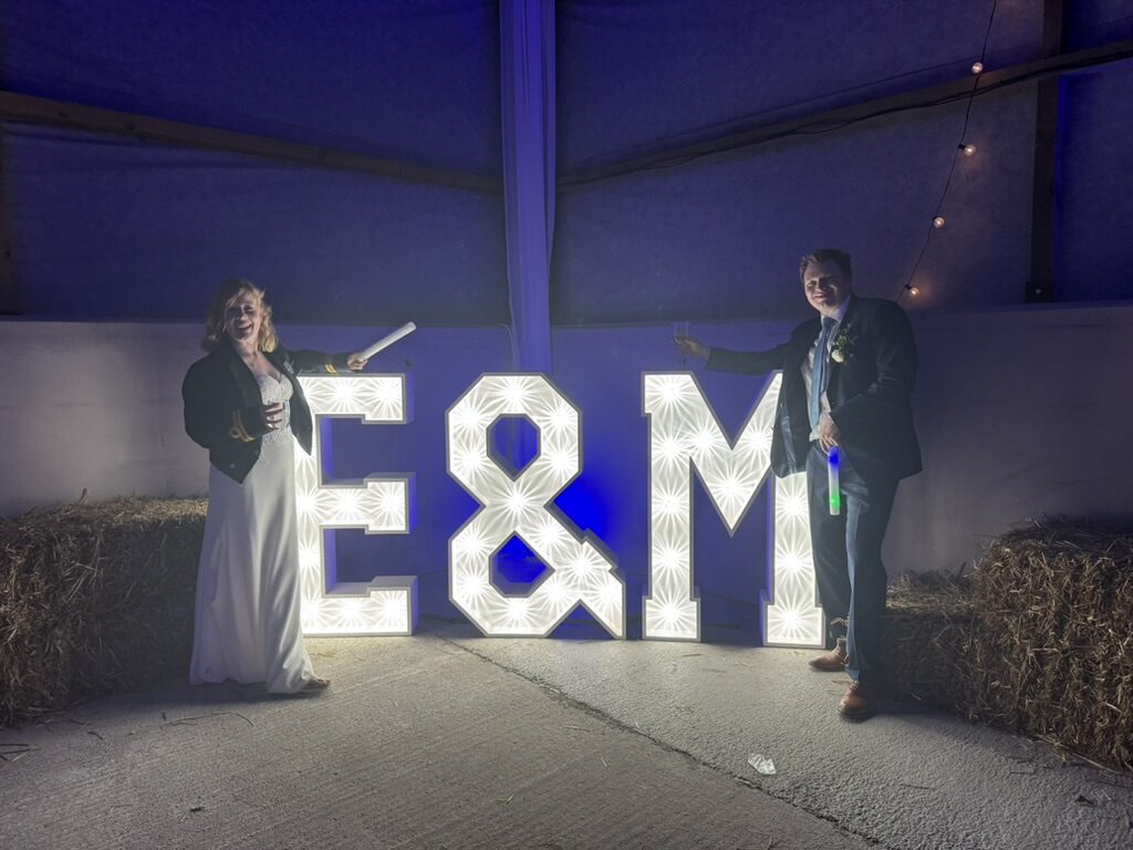 Couple beside illuminated initials inside the barn