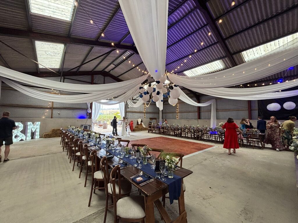 Wedding tables and a dance floor arranged inside the barn at Hewletts Farm