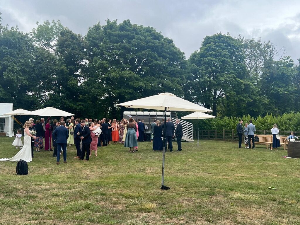 Outdoor wedding gathering in the meadow with umbrellas
